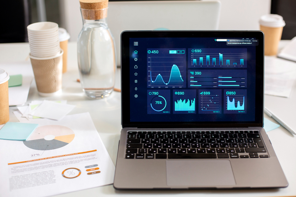 Laptop running data analysis software and a pie chart on a sheet of paper next to it all put on a work desk